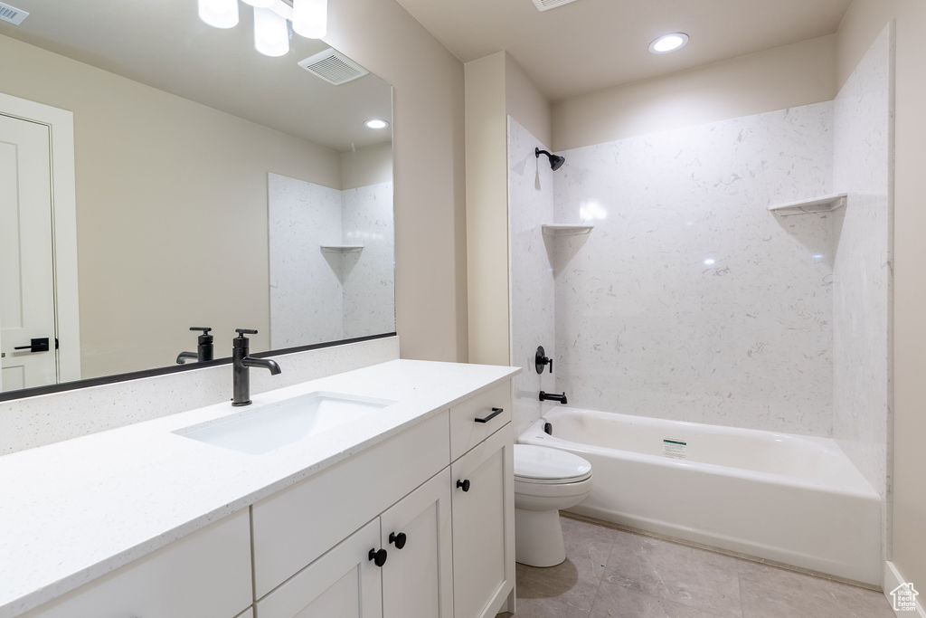 Full bathroom featuring vanity with extensive cabinet space, tiled shower / bath, toilet, and tile floors