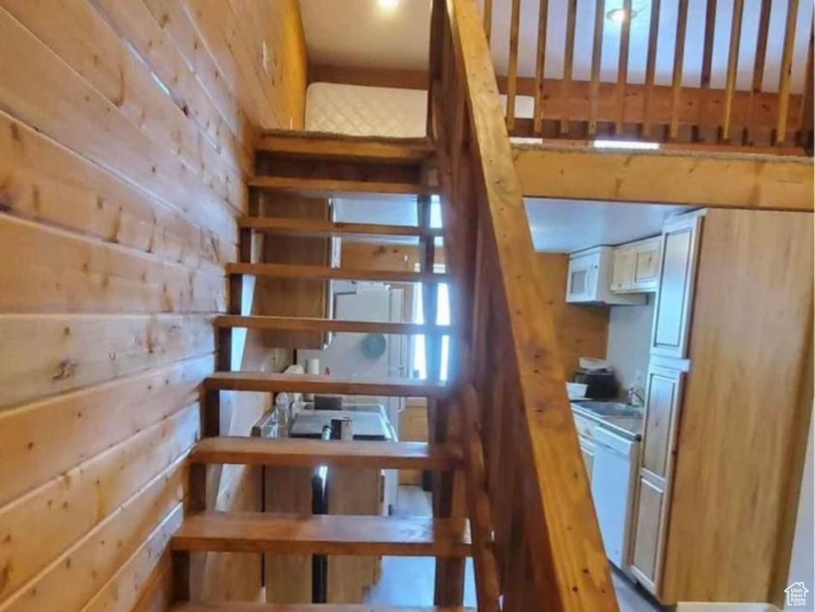 Staircase featuring hardwood / wood-style flooring and wooden walls