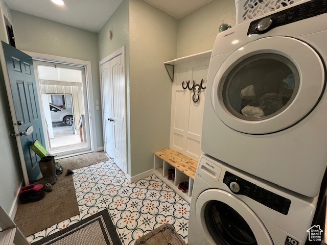 Laundry room featuring stacked washer and dryer and light tile floors