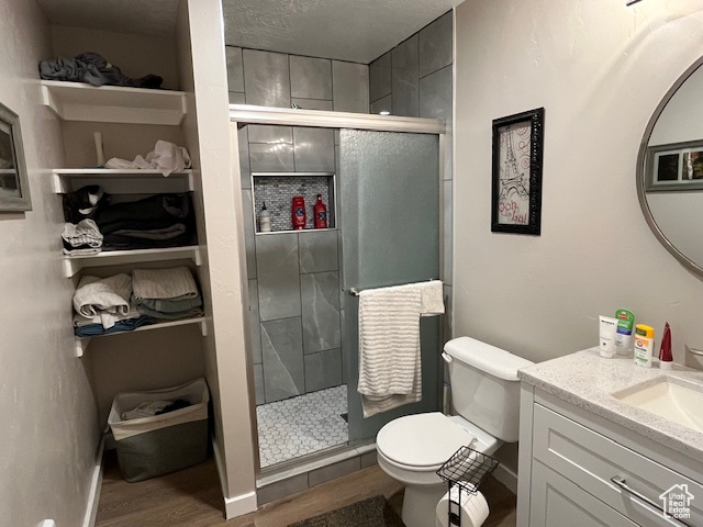Bathroom featuring walk in shower, hardwood / wood-style flooring, toilet, and large vanity