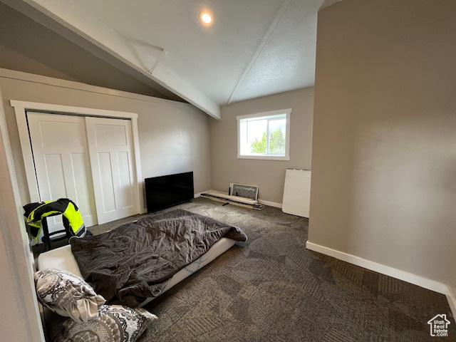 Carpeted bedroom with lofted ceiling with beams and a closet