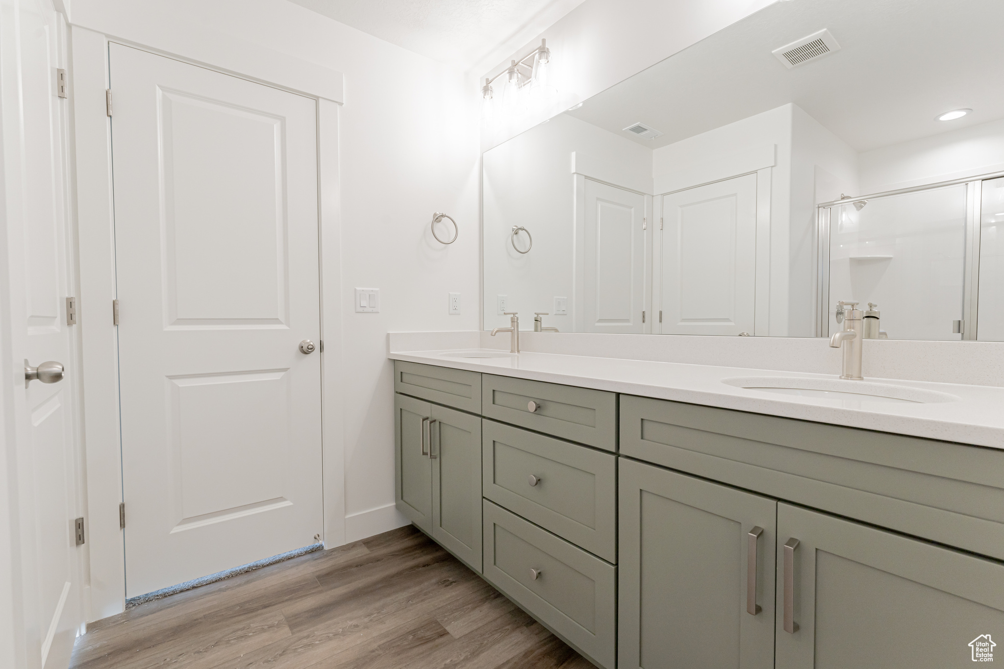 Bathroom with vanity, a shower with shower door, and wood-type flooring