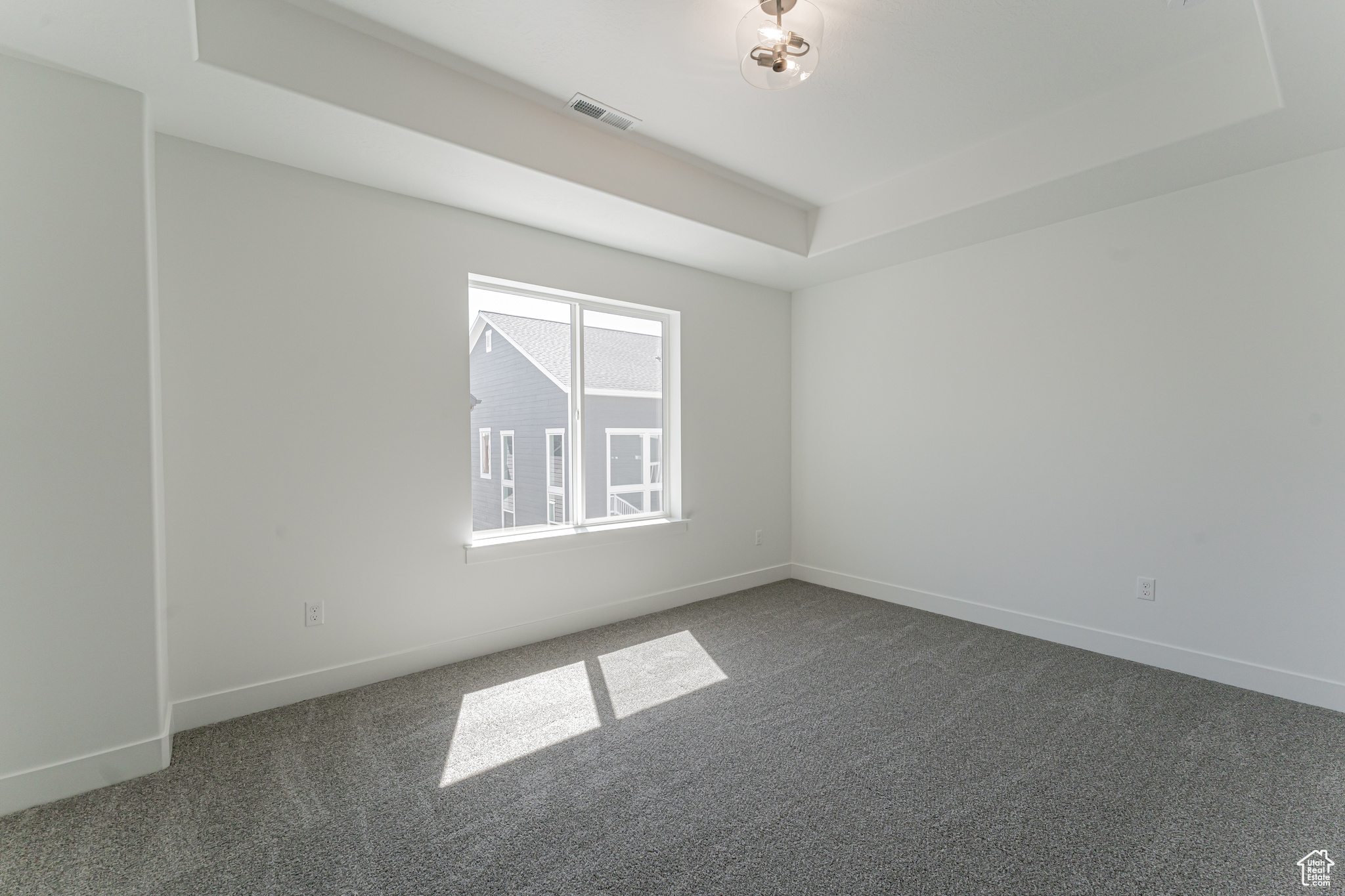 Carpeted spare room featuring a tray ceiling