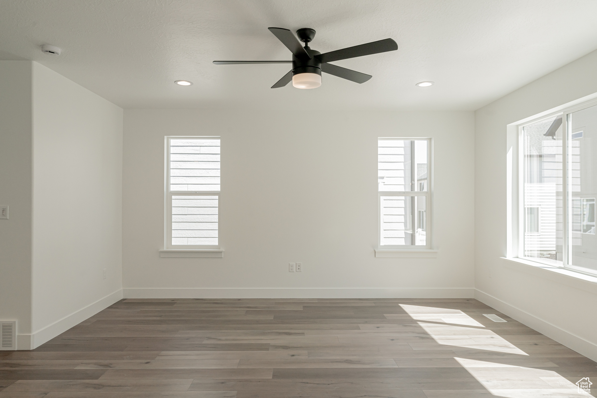 Spare room featuring light hardwood / wood-style flooring, ceiling fan, and a healthy amount of sunlight