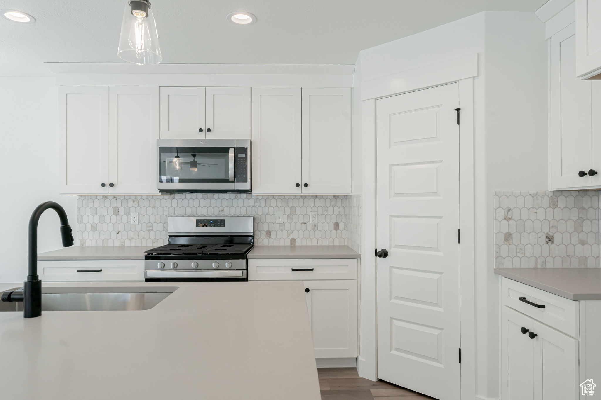 Kitchen with white cabinets, stainless steel appliances, tasteful backsplash, and sink