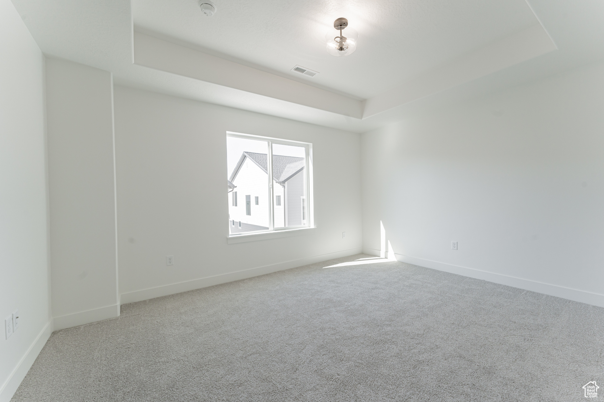 Empty room featuring a tray ceiling and carpet