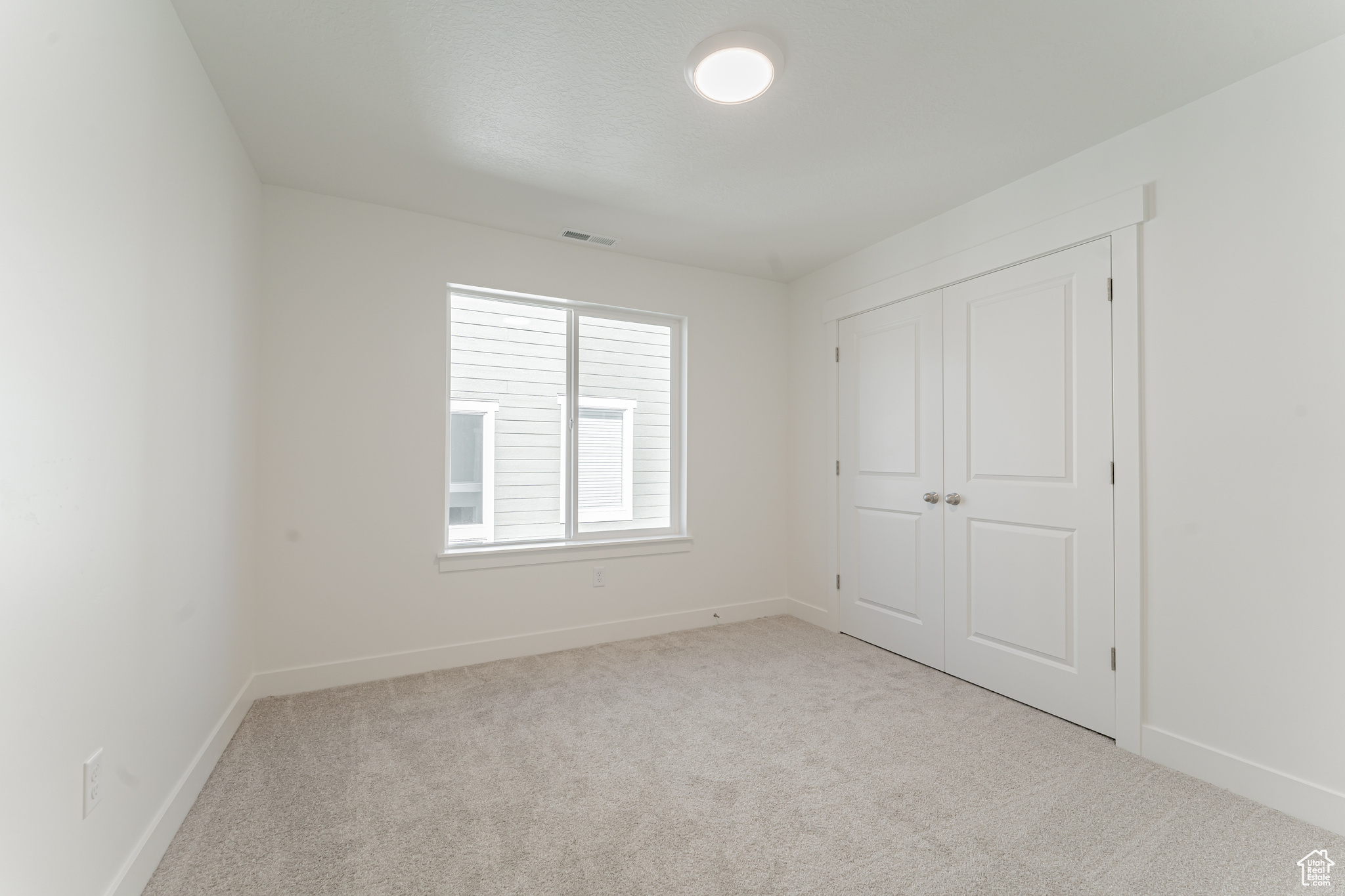 Unfurnished bedroom featuring a closet and light carpet