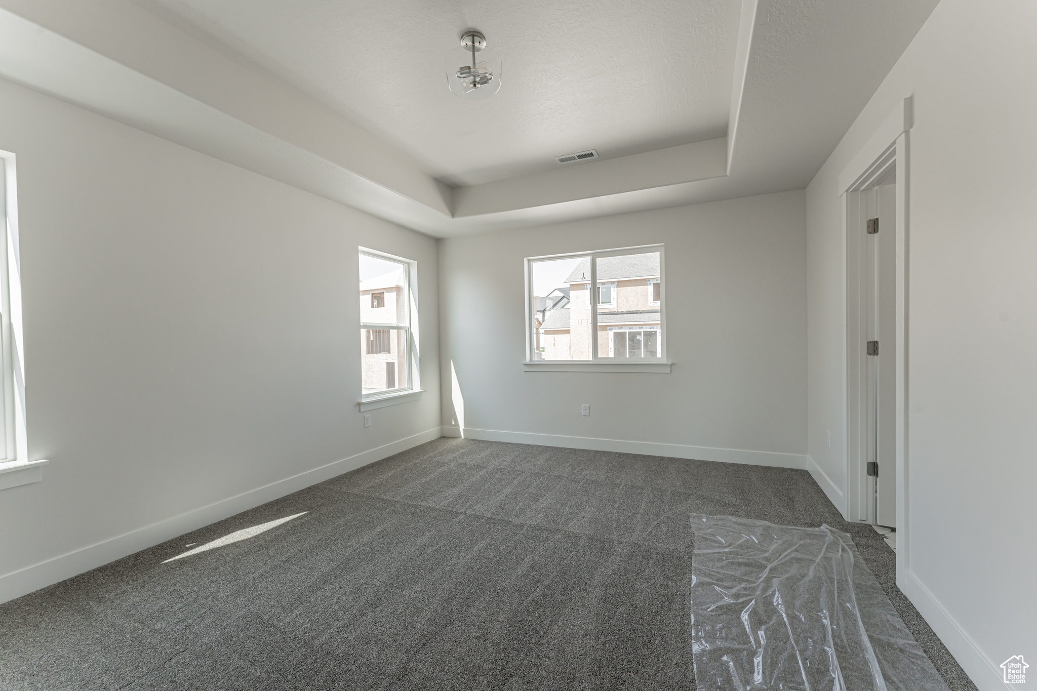 Unfurnished room with dark colored carpet and a raised ceiling