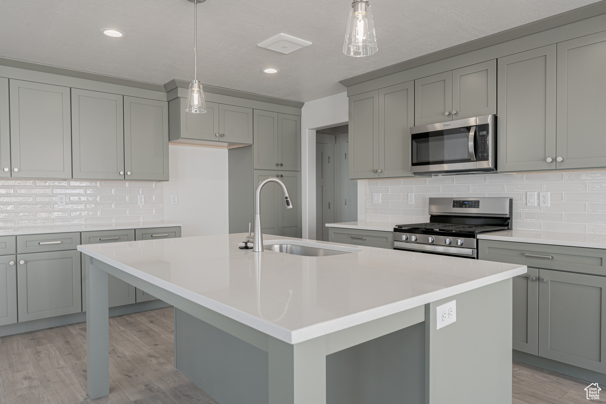 Kitchen featuring a kitchen island with sink, stainless steel appliances, and sink