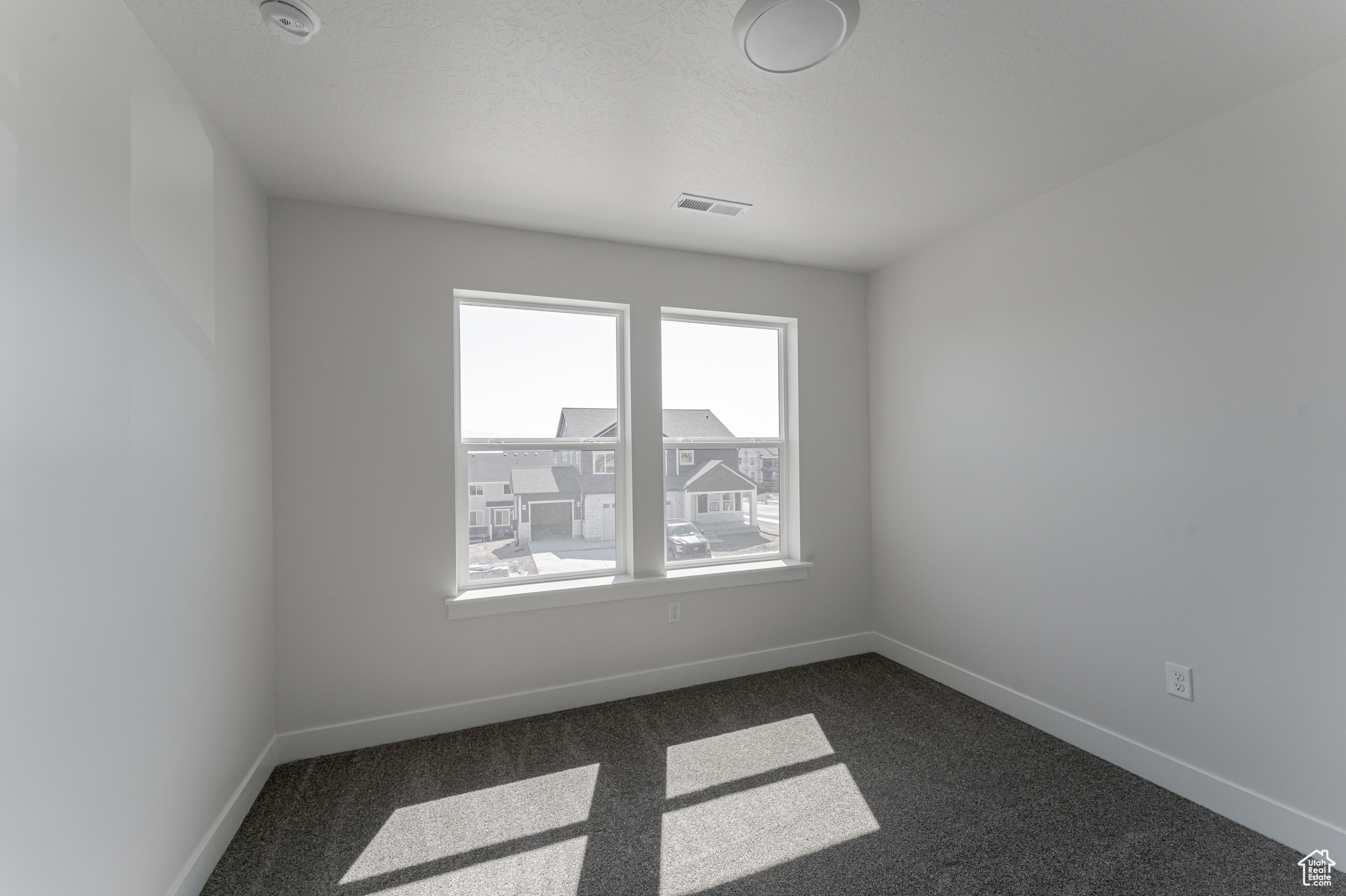 Spare room with dark carpet and a textured ceiling