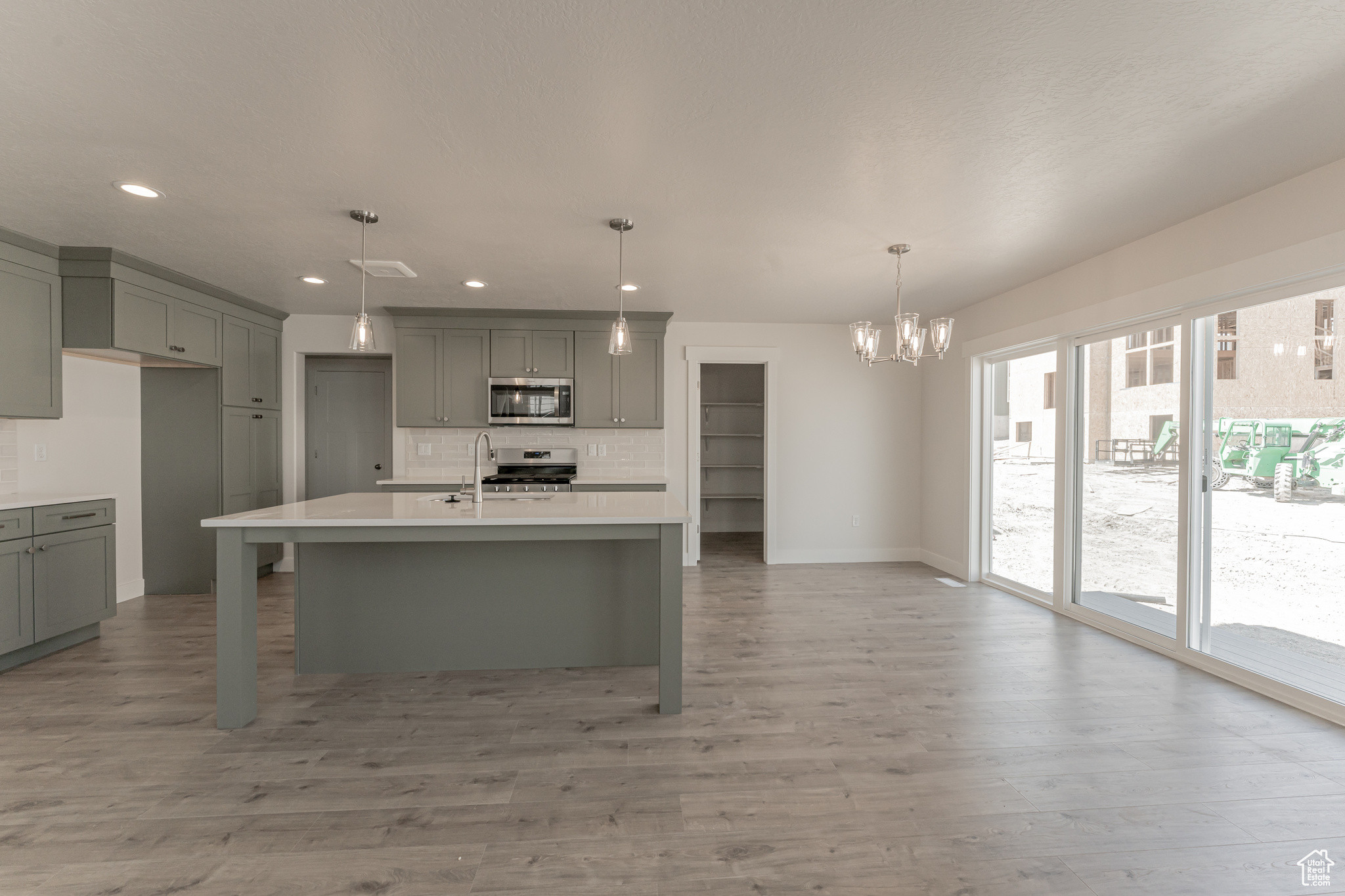 Kitchen with gray cabinets, appliances with stainless steel finishes, and wood-type flooring