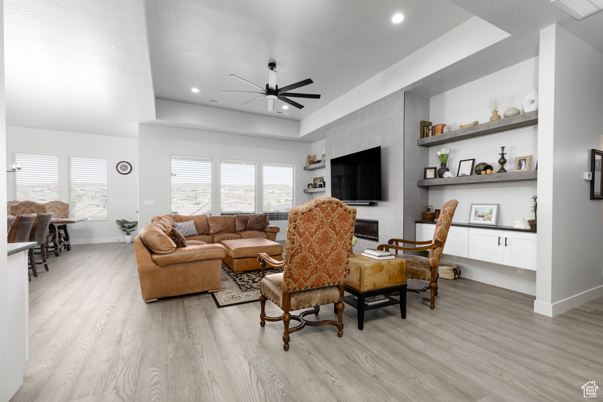 Living room featuring light hardwood / wood-style flooring, a raised ceiling, and ceiling fan