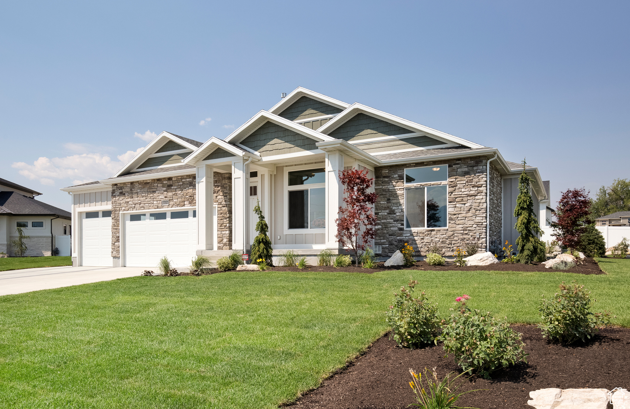 Craftsman inspired home featuring a garage and a front lawn