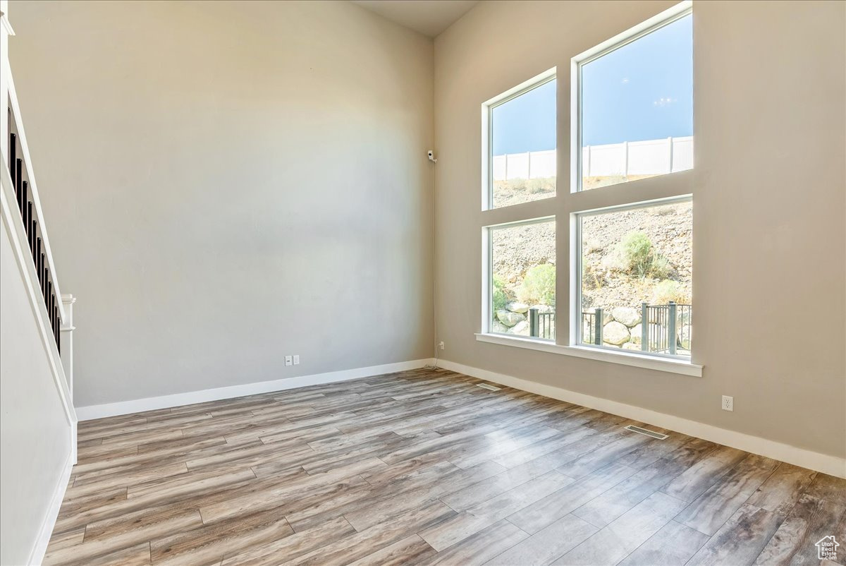 Empty room featuring a towering ceiling and light wood-type flooring