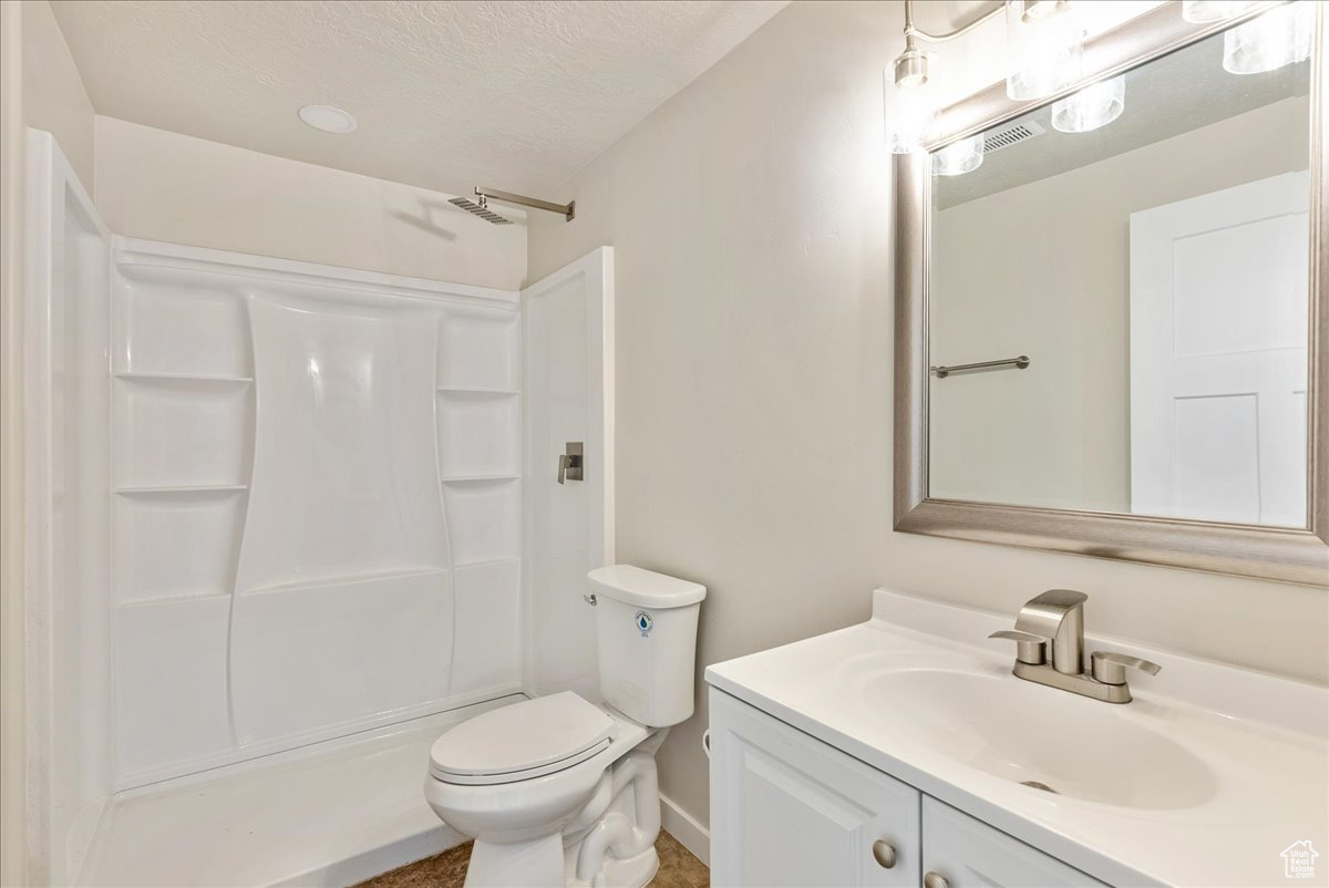 Bathroom with toilet, vanity, and walk in shower