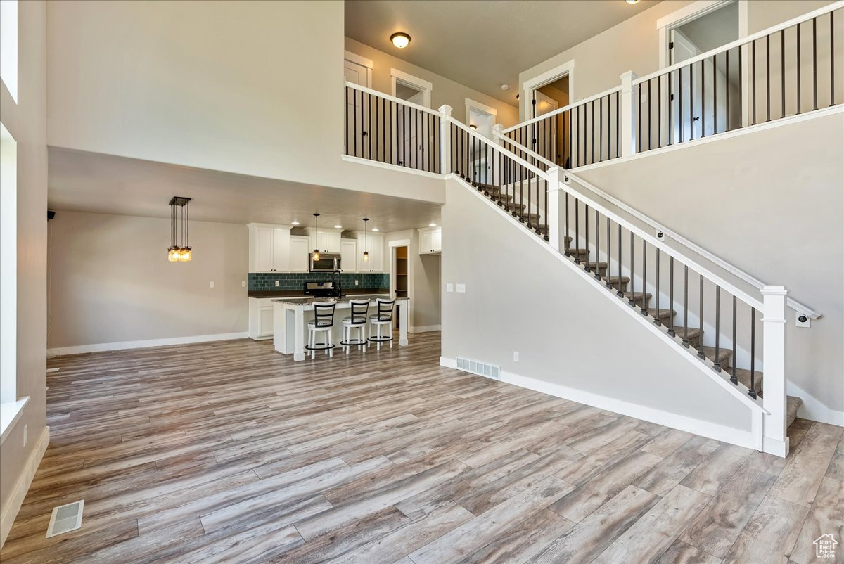 Unfurnished living room with light wood-type flooring and a high ceiling