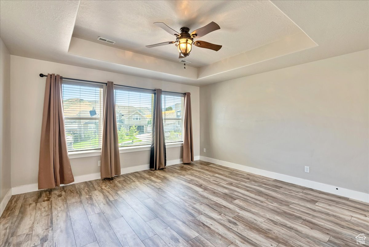 Spare room featuring ceiling fan, a raised ceiling, and wood-type flooring