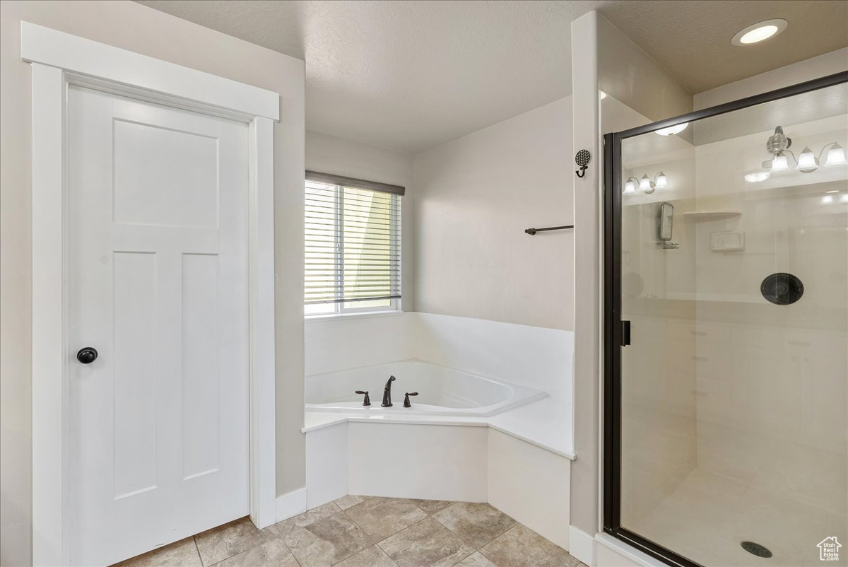 Bathroom featuring shower with separate bathtub and tile patterned flooring