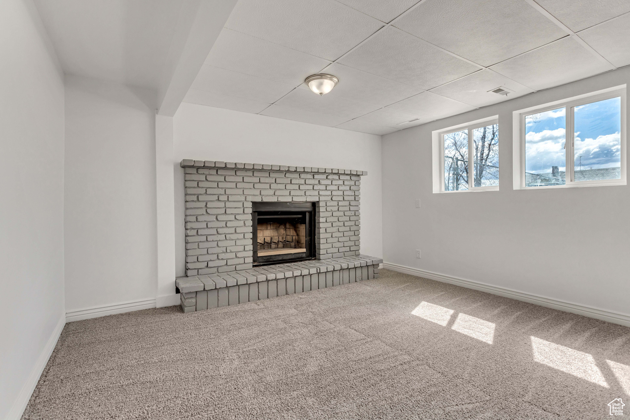 Unfurnished living room with a fireplace, carpet floors, and a drop ceiling