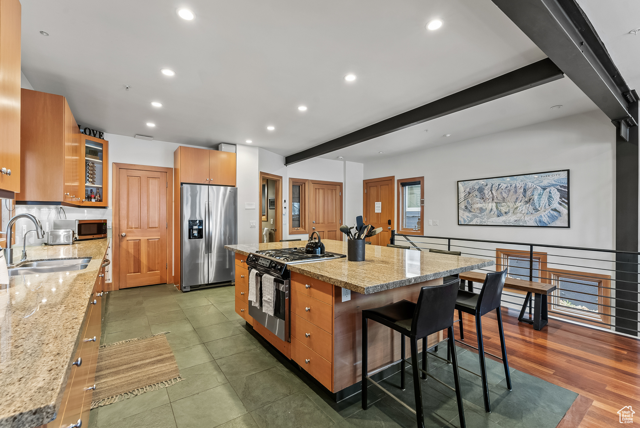 Kitchen featuring beamed ceiling, stainless steel appliances, a kitchen island, sink, and a breakfast bar area