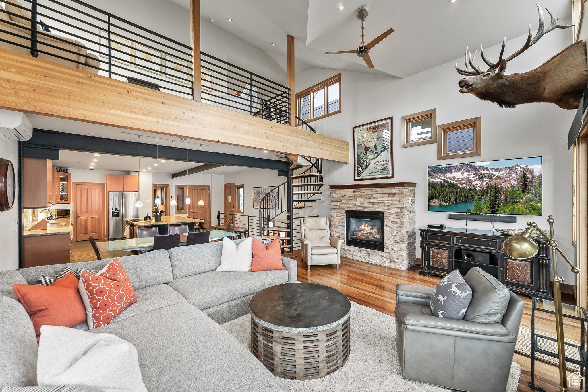 Living room featuring light hardwood / wood-style floors, a fireplace, an AC wall unit, a high ceiling, and ceiling fan