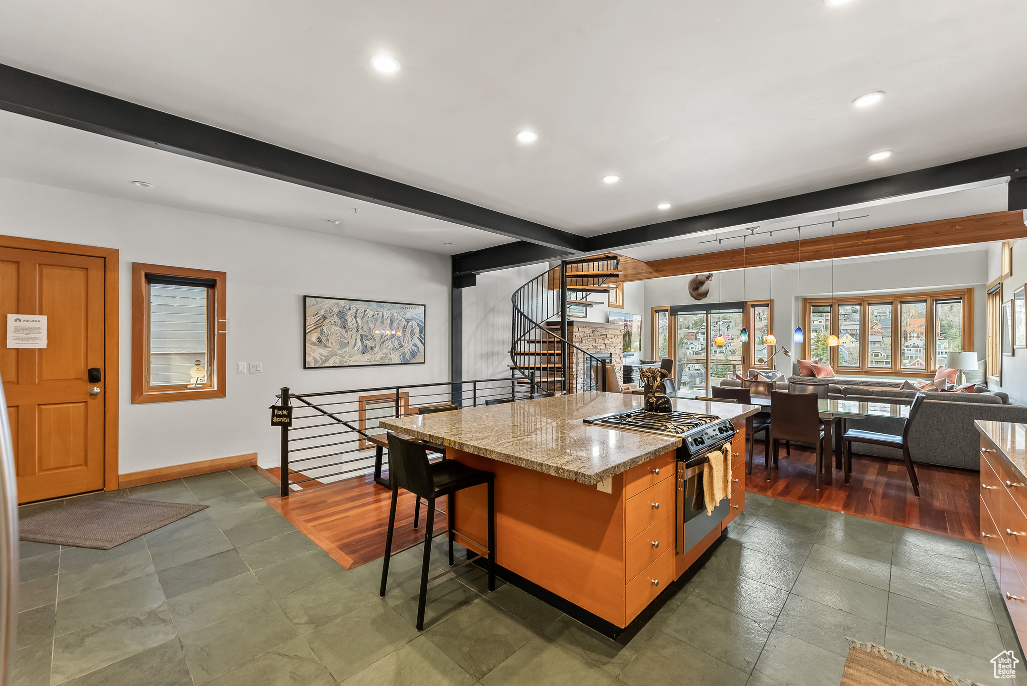 Kitchen featuring light stone counters, dark tile floors, a kitchen island, stainless steel range with gas stovetop, and beamed ceiling