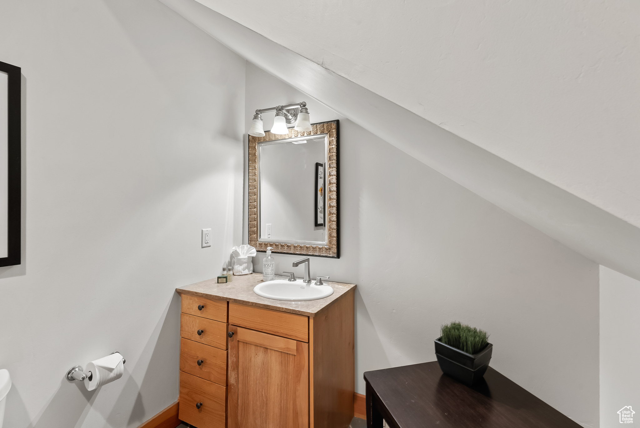 Bathroom with vaulted ceiling, vanity, and toilet