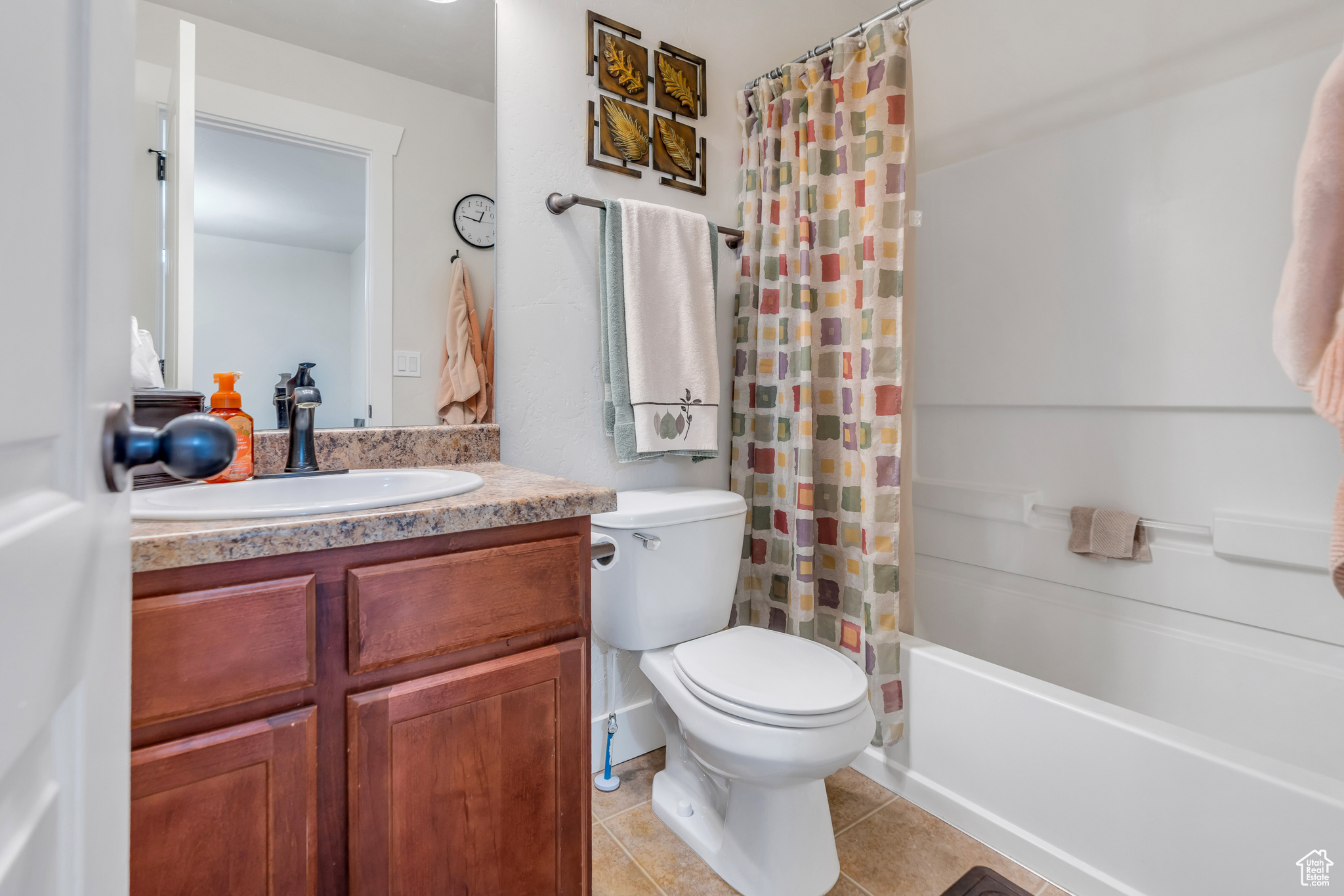 Full bathroom with shower / bath combo with shower curtain, tile flooring, vanity, and toilet