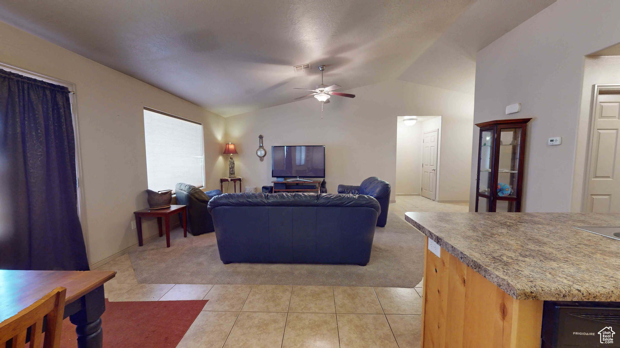 Tiled living room featuring ceiling fan and lofted ceiling