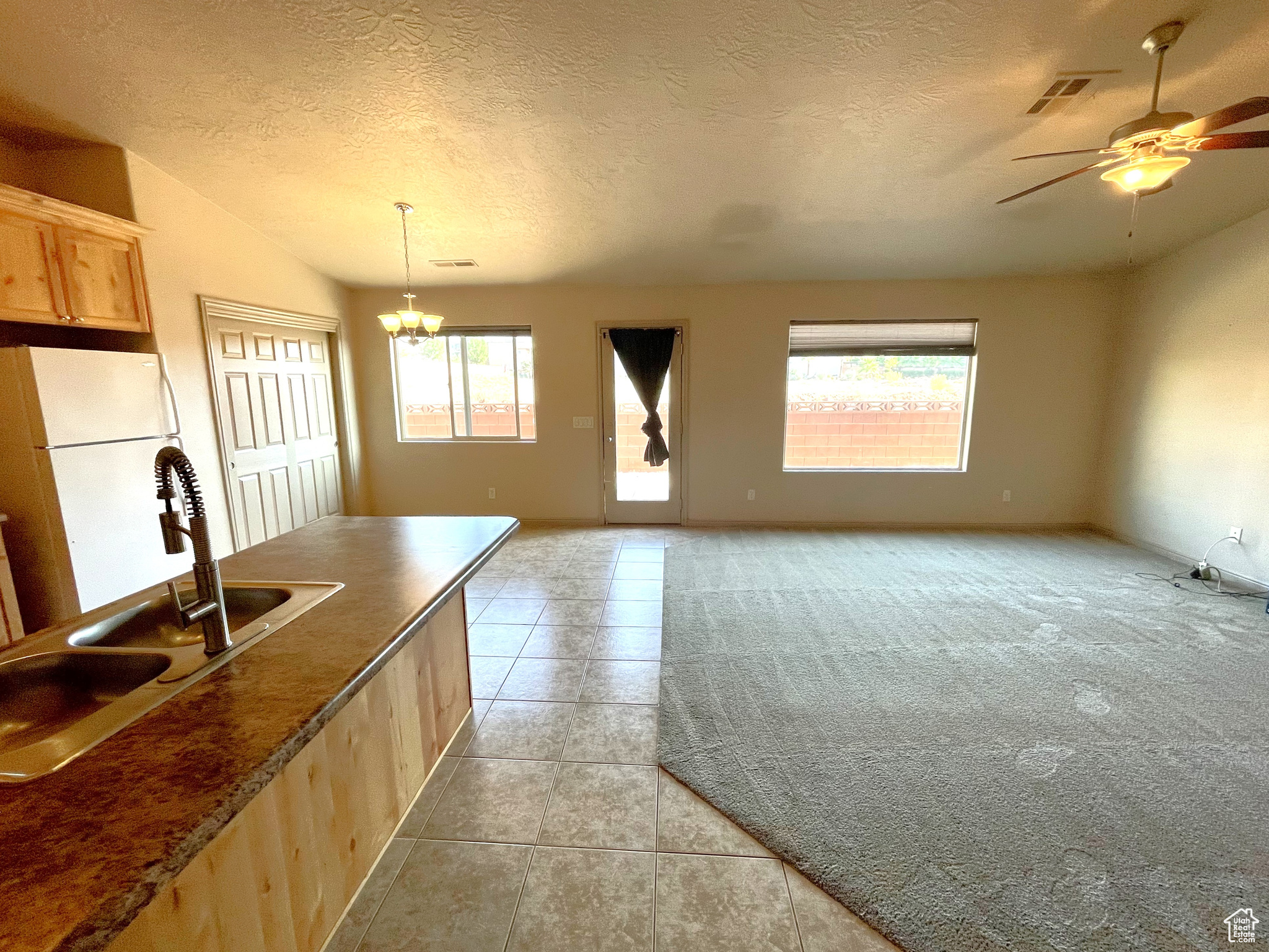 Kitchen featuring a wealth of natural light, light brown cabinetry, light carpet, and white refrigerator