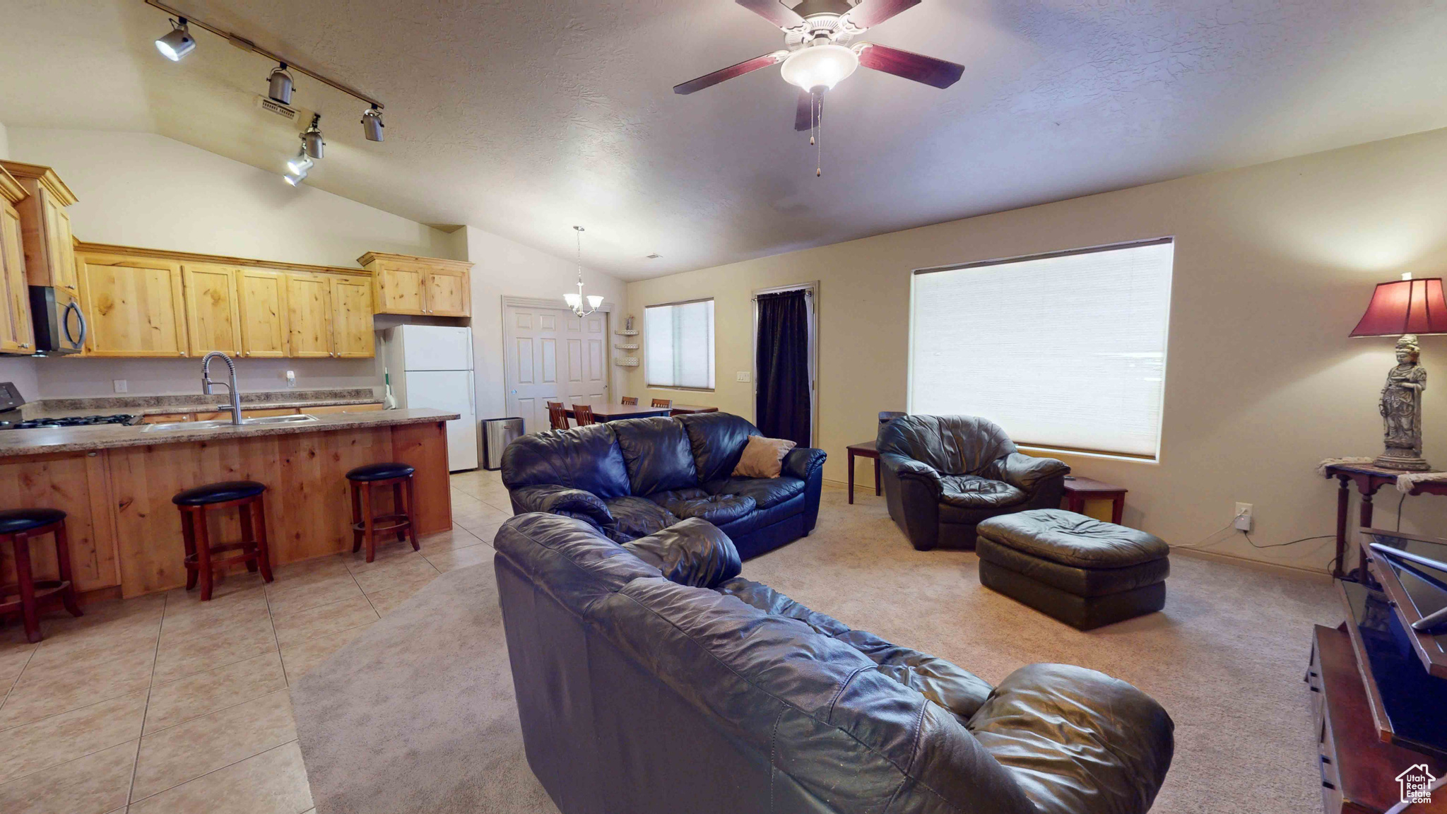 Tiled living room featuring vaulted ceiling, sink, ceiling fan, and track lighting