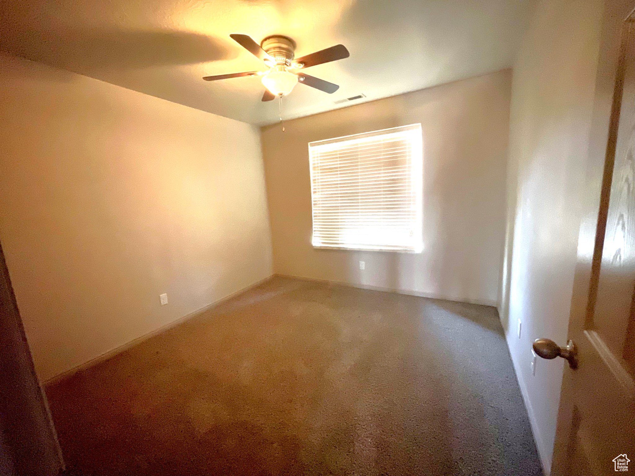 Empty room featuring carpet flooring and ceiling fan