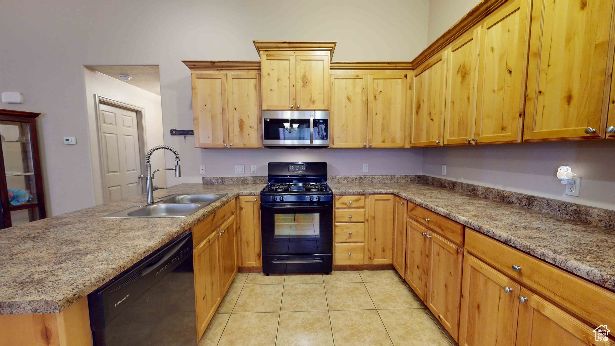 Kitchen featuring black appliances, sink, and light tile floors