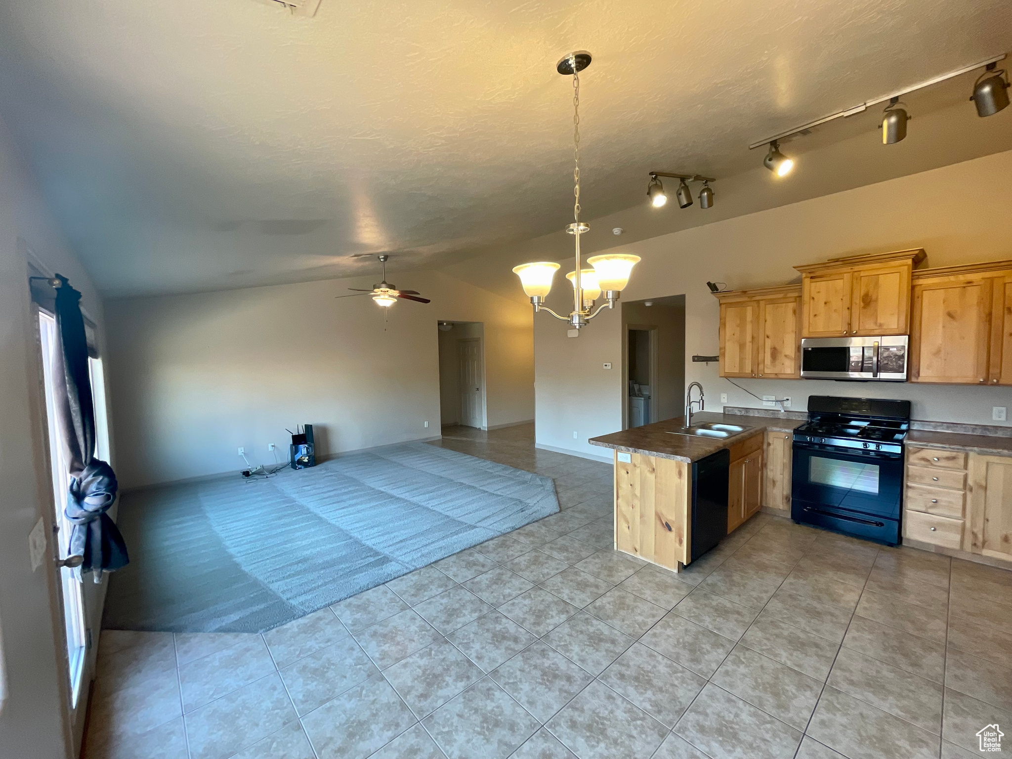 Kitchen featuring rail lighting, lofted ceiling, sink, and black appliances