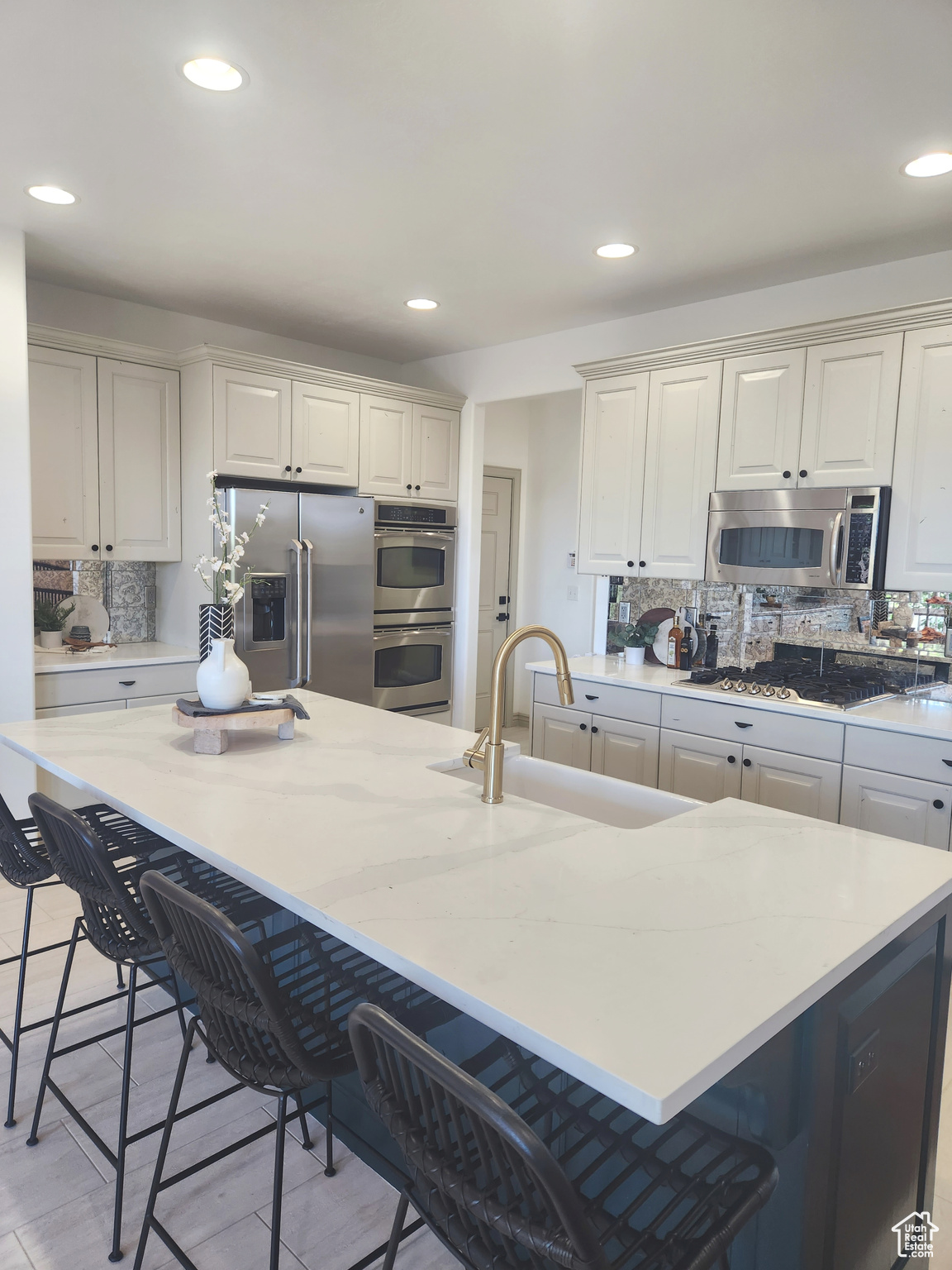 Kitchen featuring a kitchen island, a kitchen breakfast bar, tasteful backsplash, and appliances with stainless steel finishes