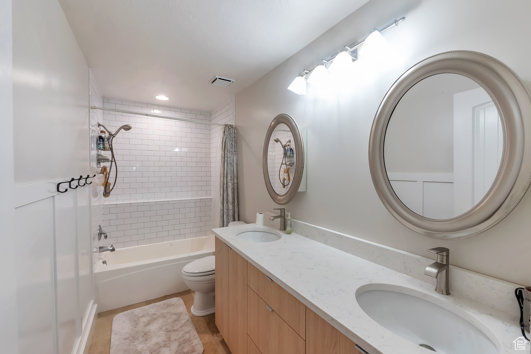 Full bathroom featuring tile floors, shower / tub combo, toilet, and dual bowl vanity