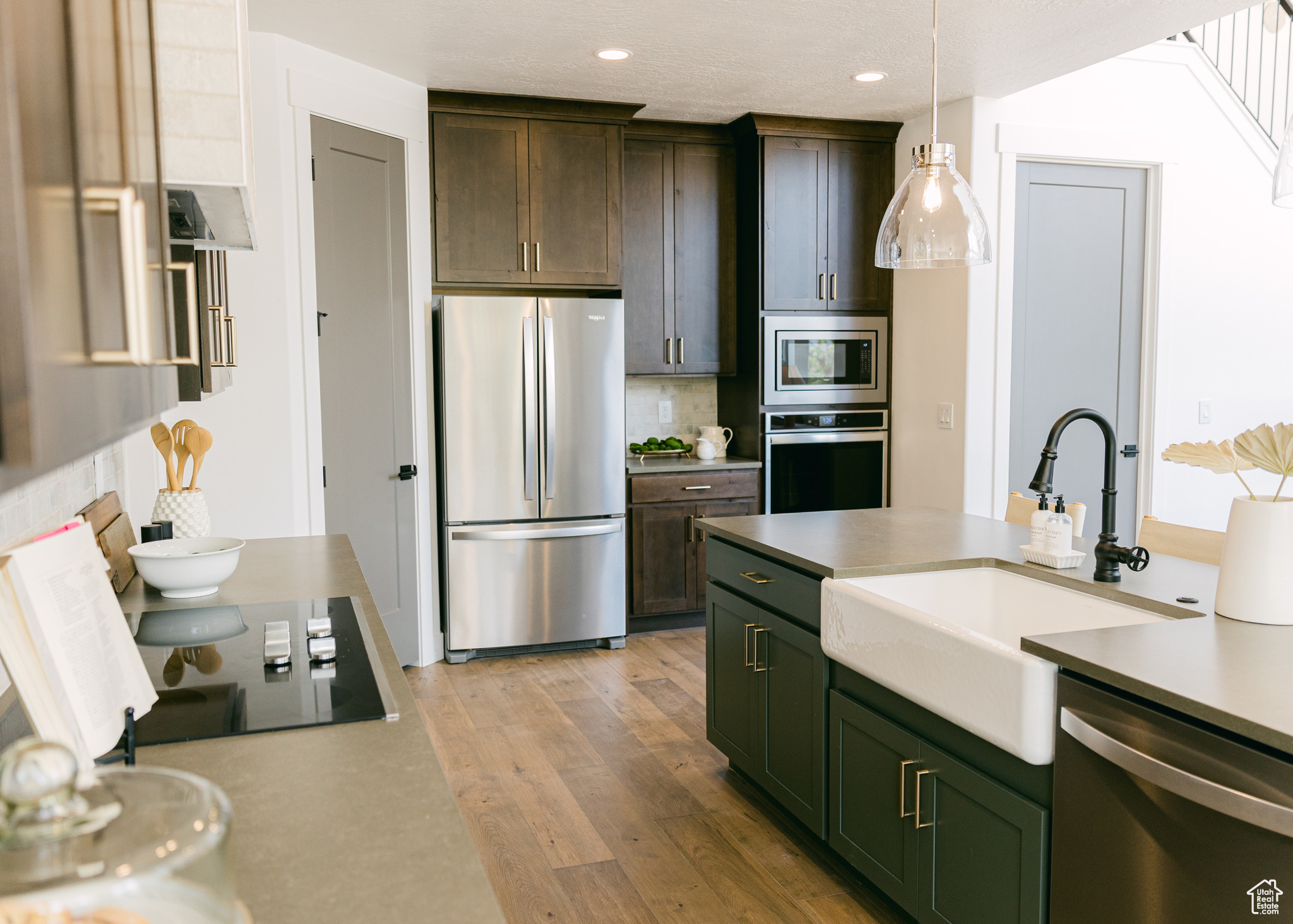 Kitchen with light hardwood / wood-style floors, tasteful backsplash, pendant lighting, sink, and appliances with stainless steel finishes