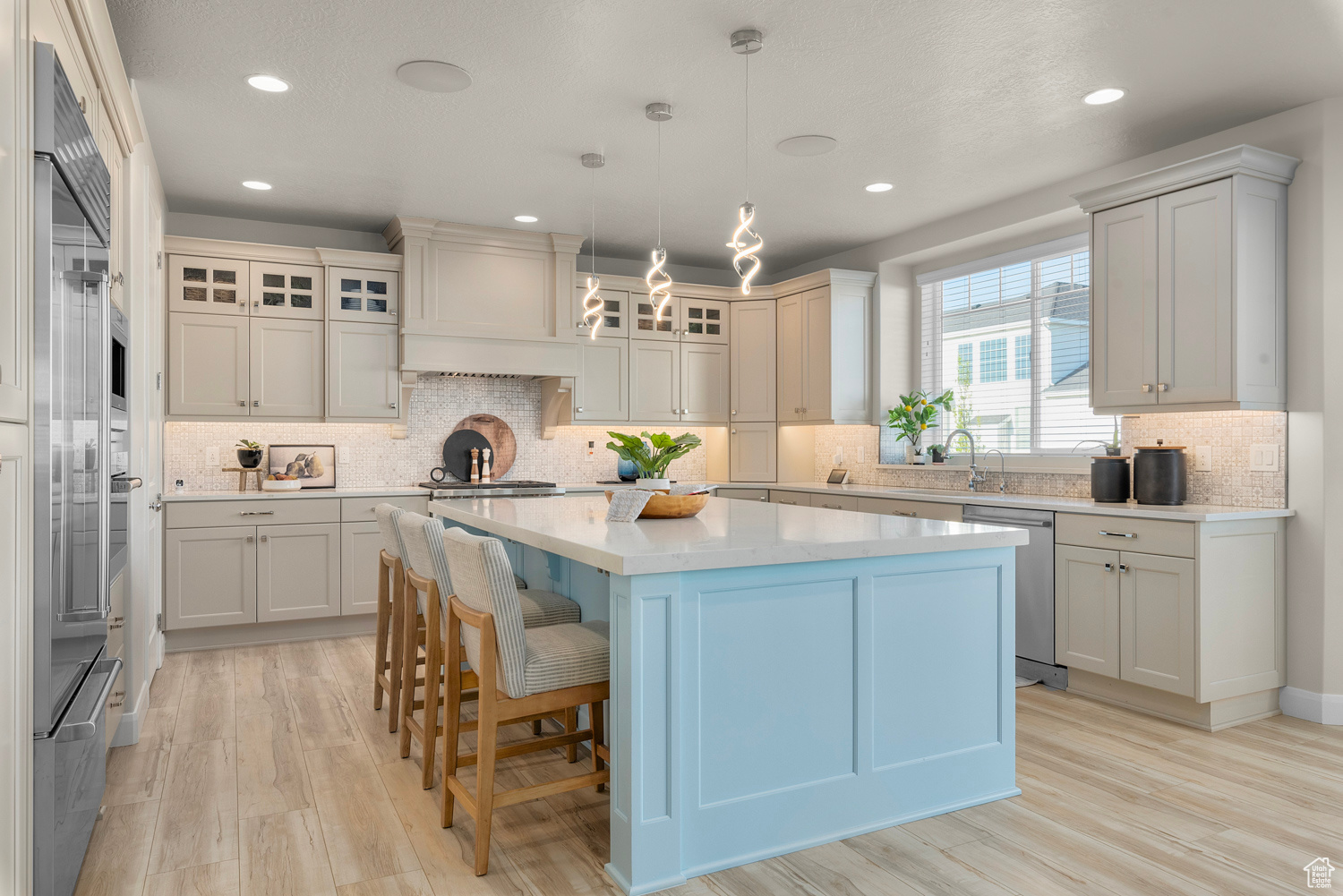 Kitchen with large island, Wolf and Sub Zero stainless steel applicances, LED light fixtures, custom tile backsplash, and custom exhaust hood