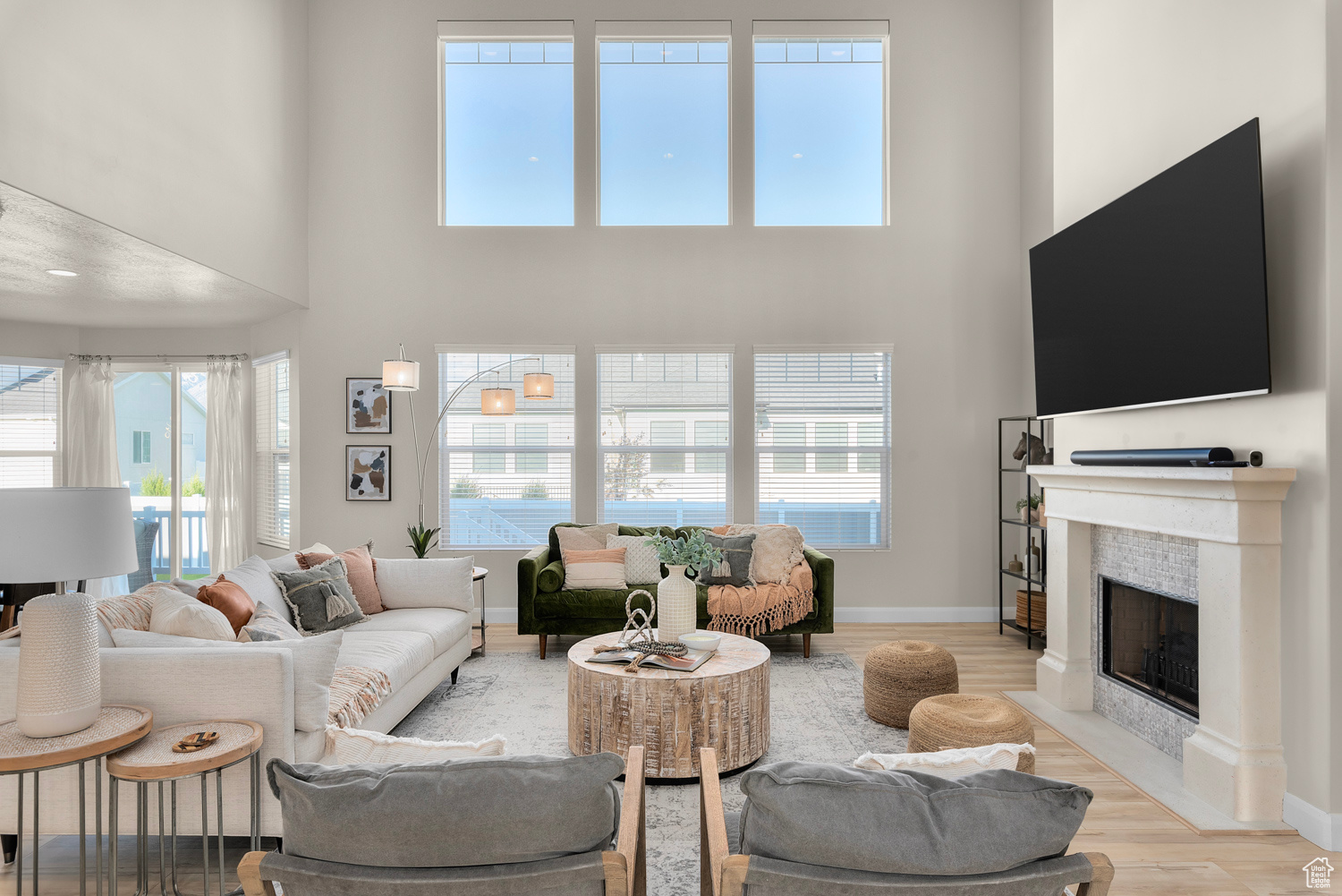 Living room with brand new upgraded LVP wood-style floors, tile fireplace surround, wood burning fireplace, 2 story windows and a high ceiling. 80