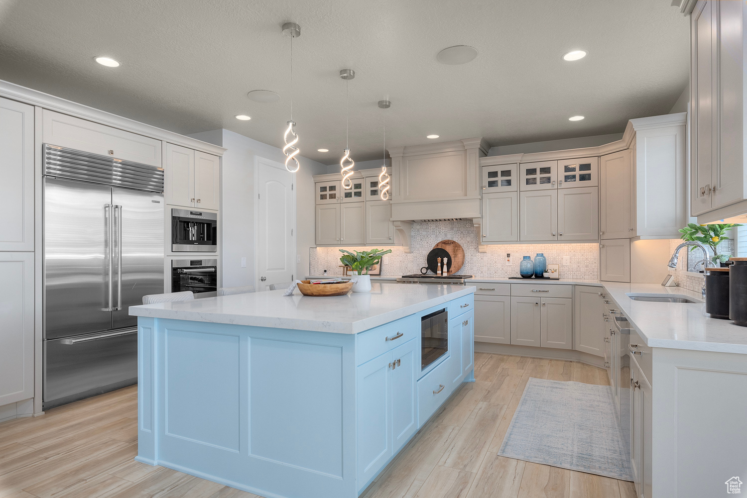 Kitchen featuring custom exhaust hood, built in Wolf & Sub Zero appliances, custom tile backsplash, a center island