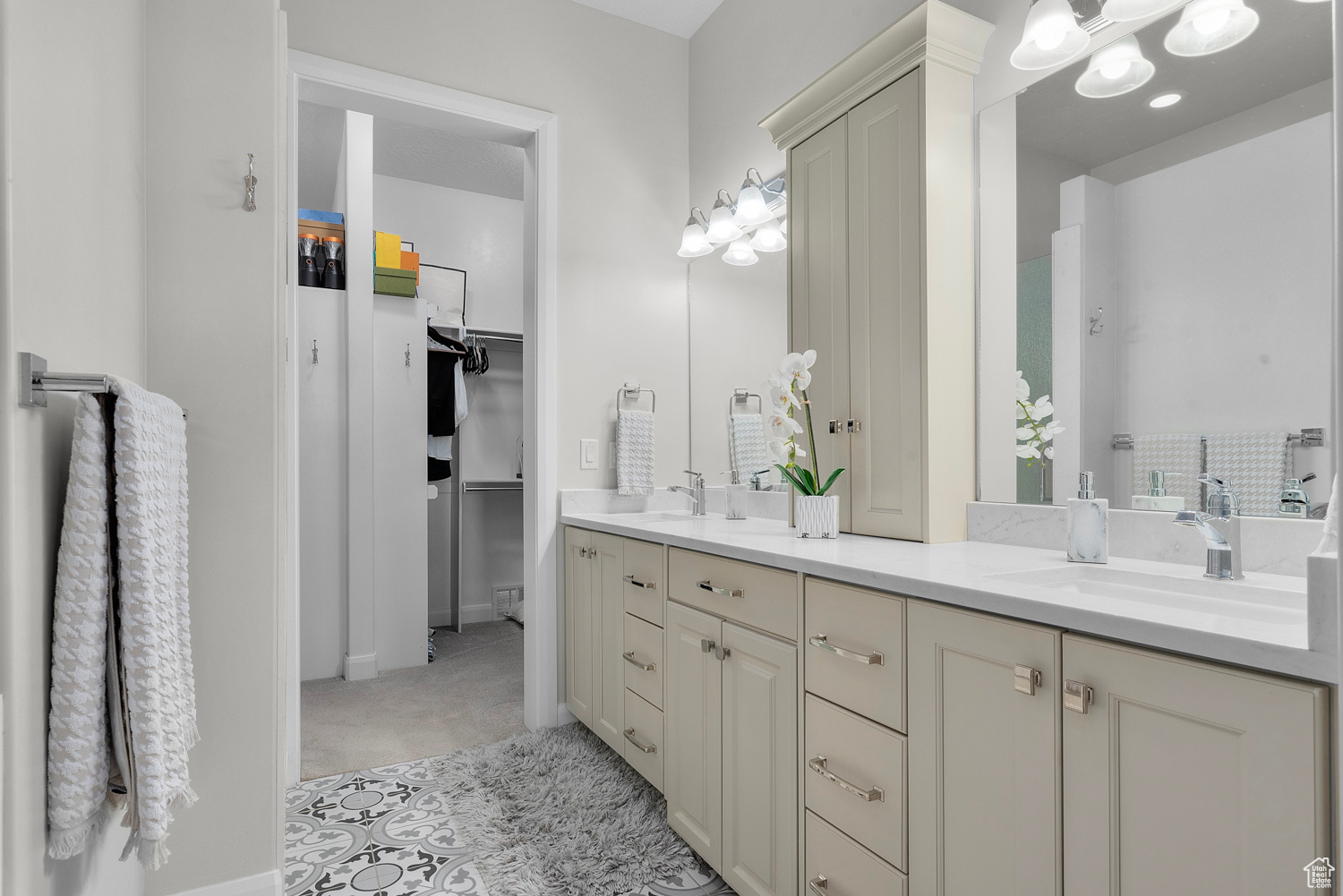 Primary En Suite Bathroom featuring double sink vanity, tile floors, his and her closets with stackable washer & dryer included