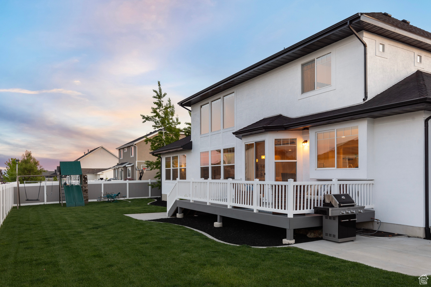 Back of house looking south at dusk featuring swing set and play equipment (included), and gas grill (included) with gas line