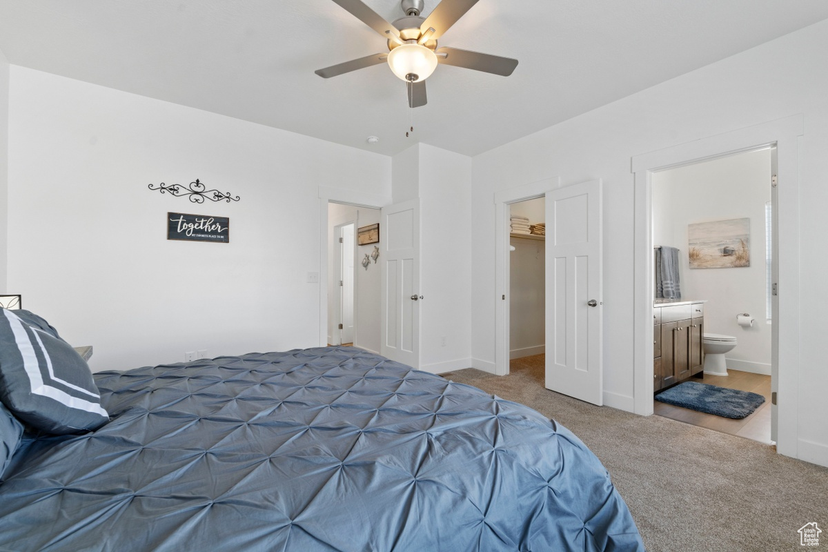 Tiled bedroom featuring ceiling fan, a closet, ensuite bath, and a spacious closet