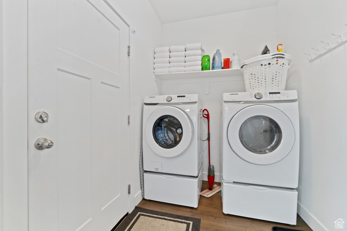 Clothes washing area with dark hardwood / wood-style flooring and washing machine and clothes dryer