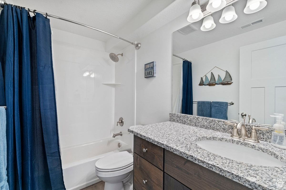 Full bathroom with shower / bath combination with curtain, vanity, and toilet