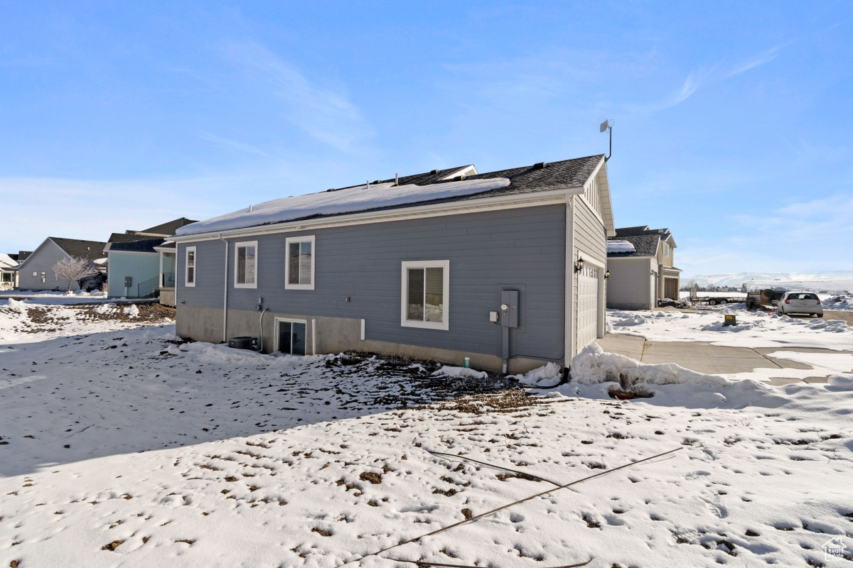 Snow covered property featuring a garage and solar panels