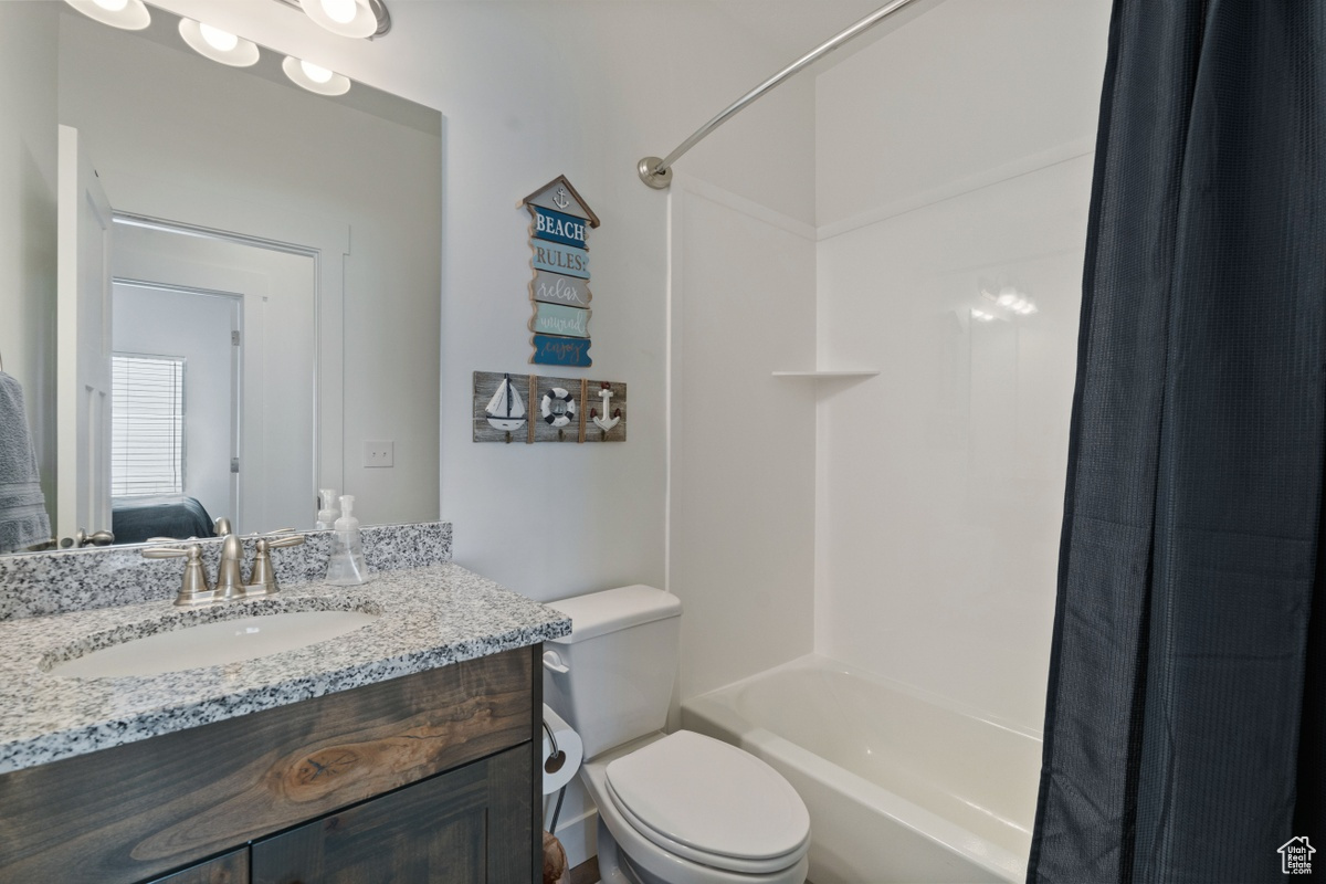 Full bathroom featuring shower / bathtub combination with curtain, vanity, and toilet