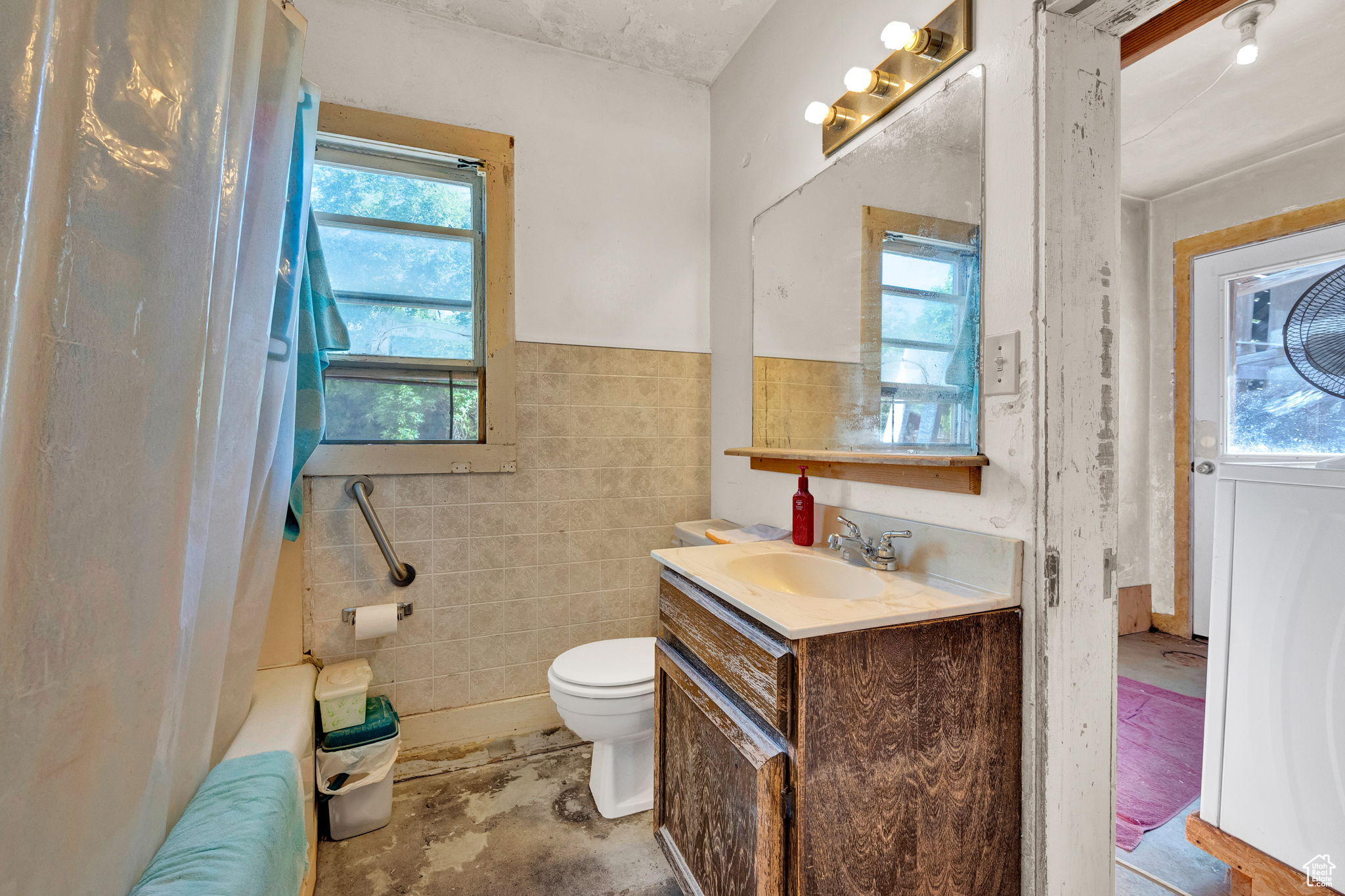 Bathroom with vanity, toilet, and tile walls