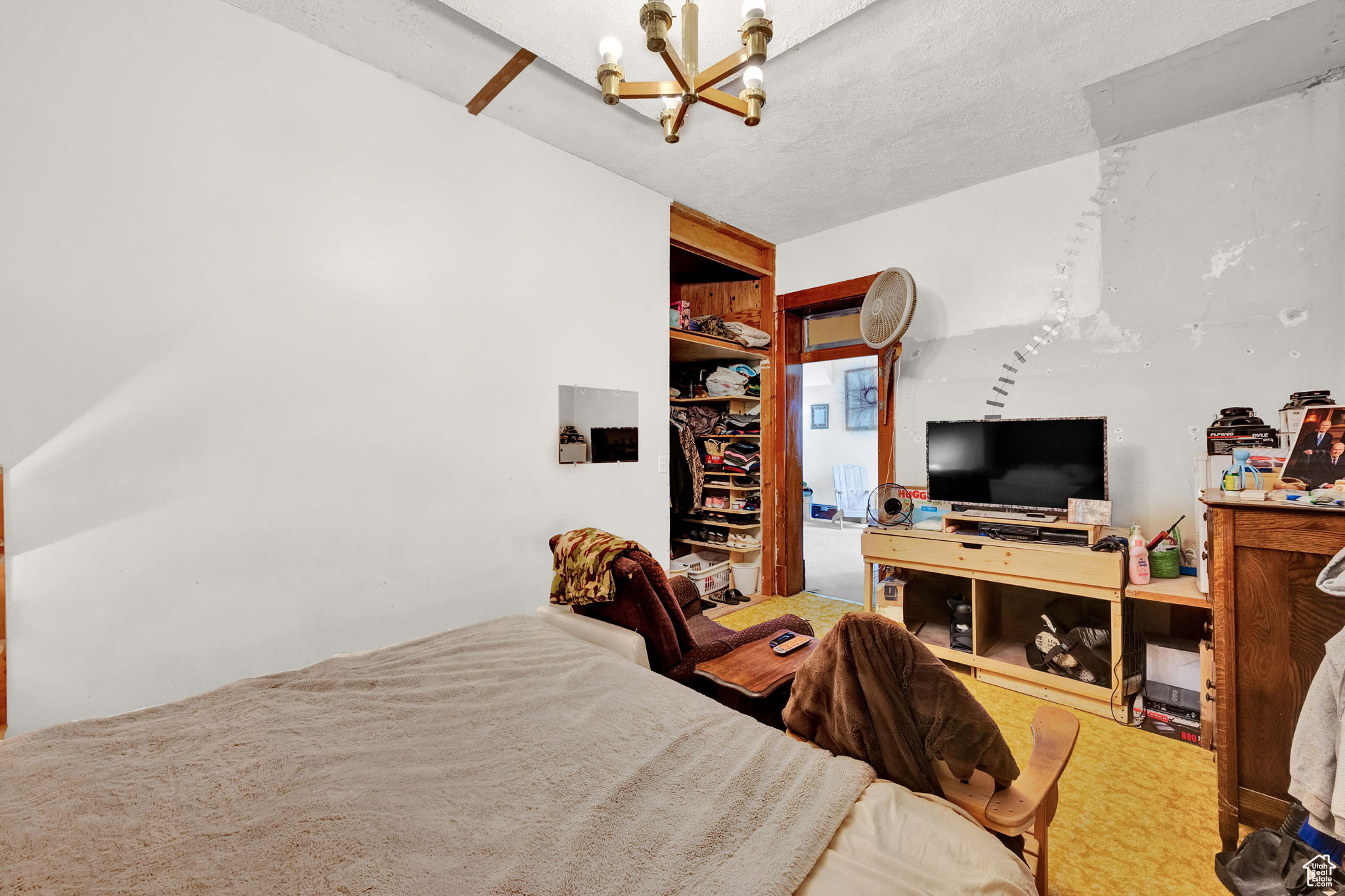 Carpeted bedroom featuring a notable chandelier and a textured ceiling