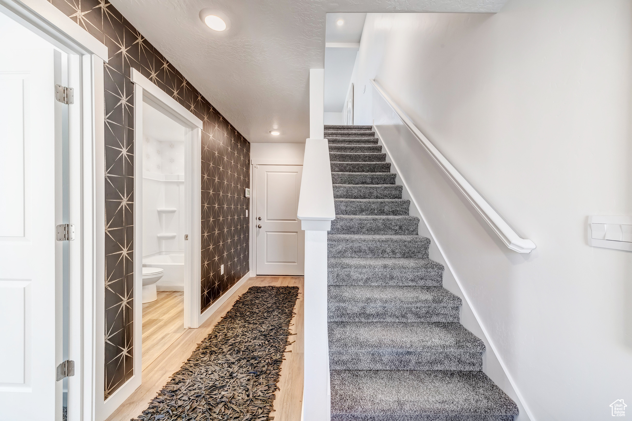 Staircase with light hardwood / wood-style flooring and tile walls